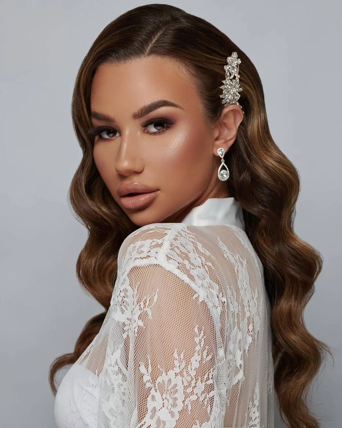 Long brunette hair set in polished Hollywood waves with a crystal hair comb.