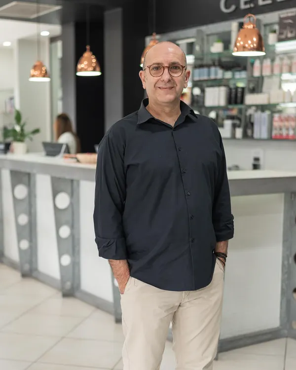 Costa, senior stylist at Cello Hairdressers, standing in front of the reception desk.