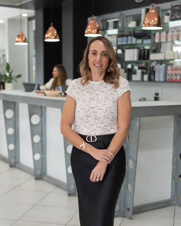 Michelle, salon manager and senior stylist at Cello Hairdressers, standing in front of the reception desk.