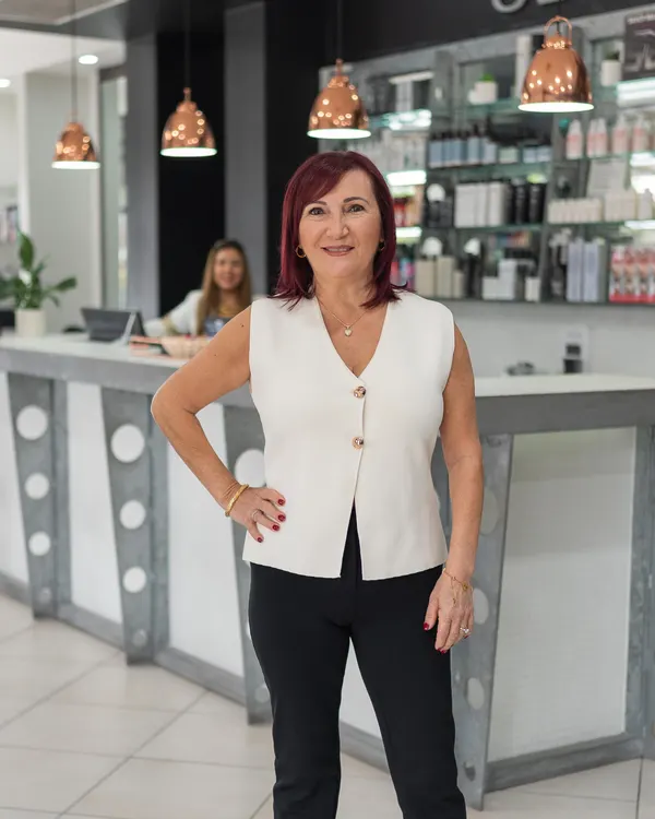 Nuccia, receptionist at Cello Hairdressers, standing in front of the reception desk.