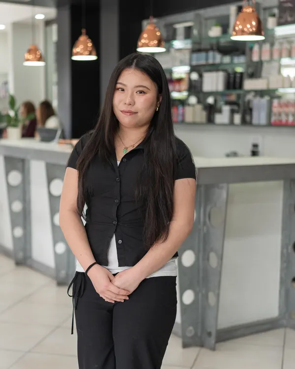 Olivia, salon assistant at Cello Hairdressers, standing in front of the reception desk.