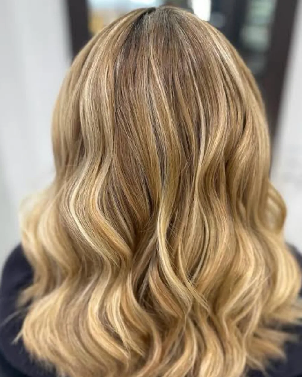 Mid-length hair with a soft golden blonde balayage, waved out at Cello Hairdressers in Five Dock.
